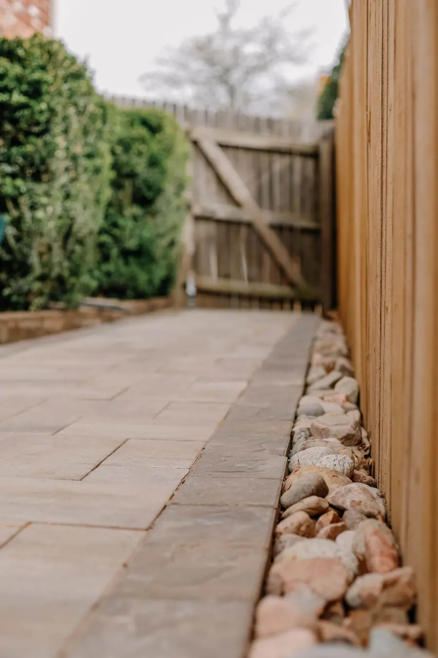 Allée de dalles de pavé le long d'une clôture de bois